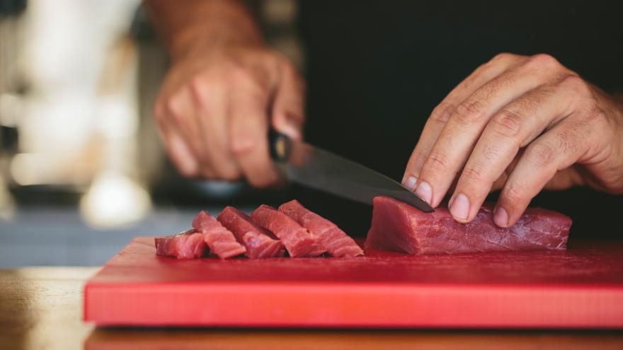 Hände schneiden Fleisch auf Küchenbrett