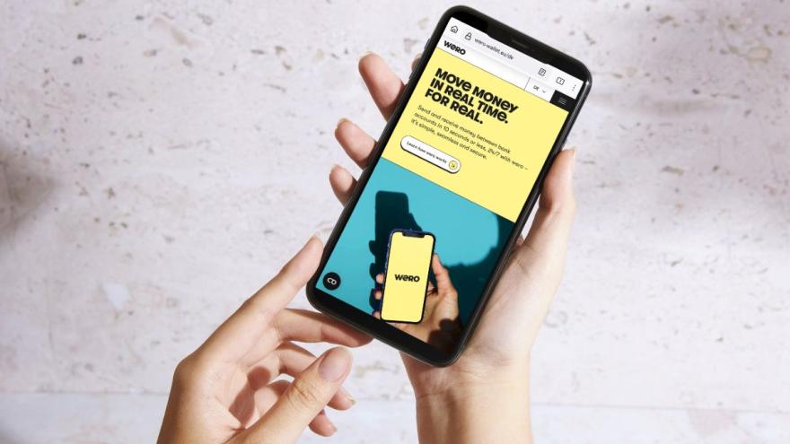 Zwei Hände halten ein Smartphone, auf dem Display ist die Internetseite von Wero zu sehen